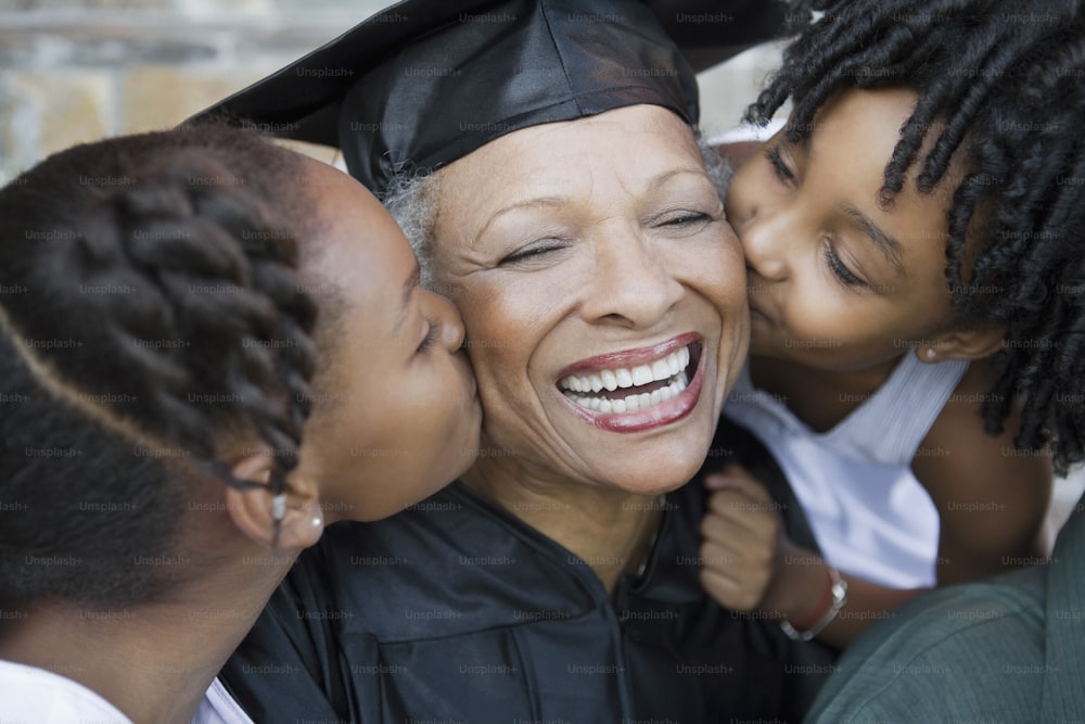 子供にキスをする卒業式のガウンを着た女性