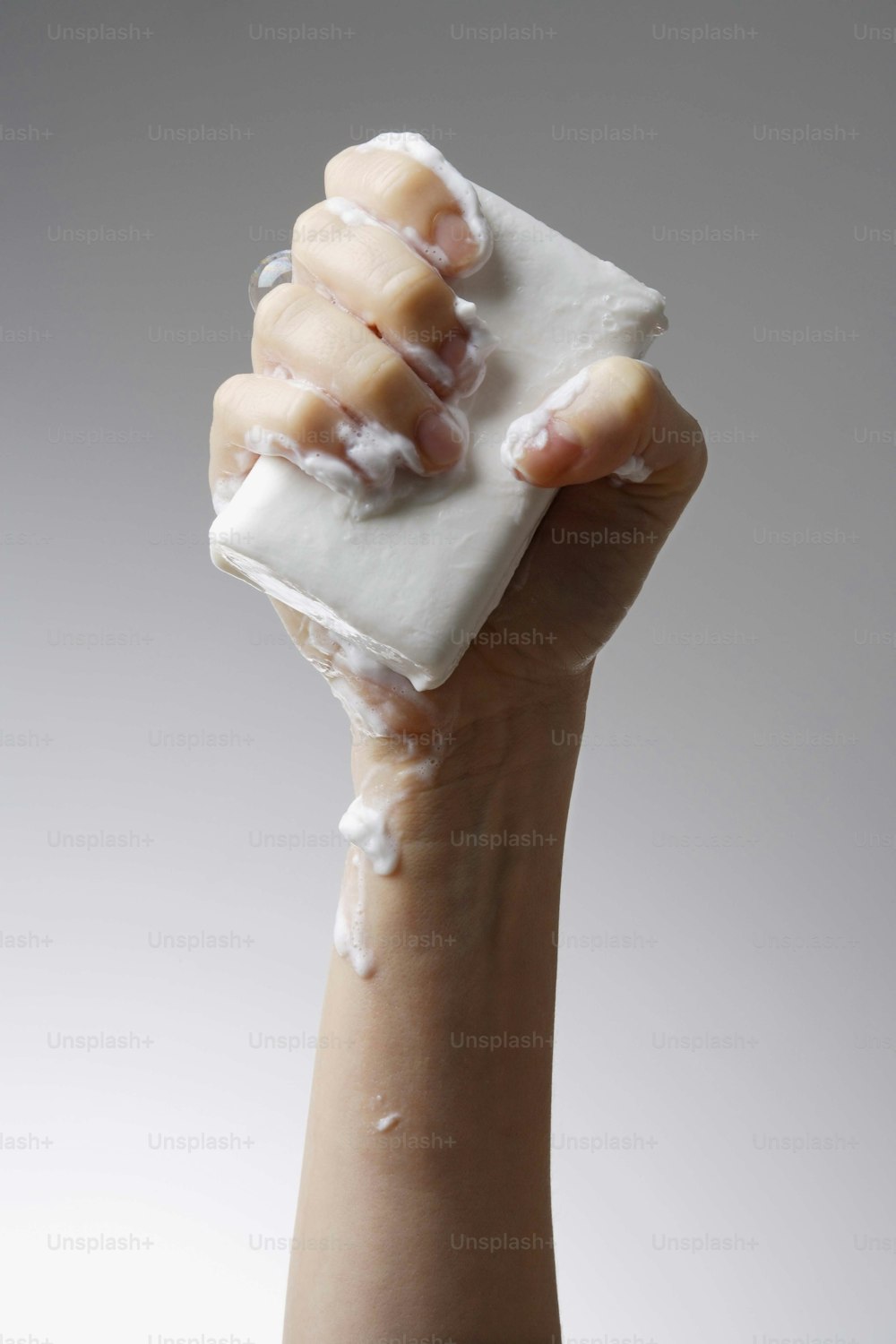 una mano sosteniendo un cuadrado de jabón blanco