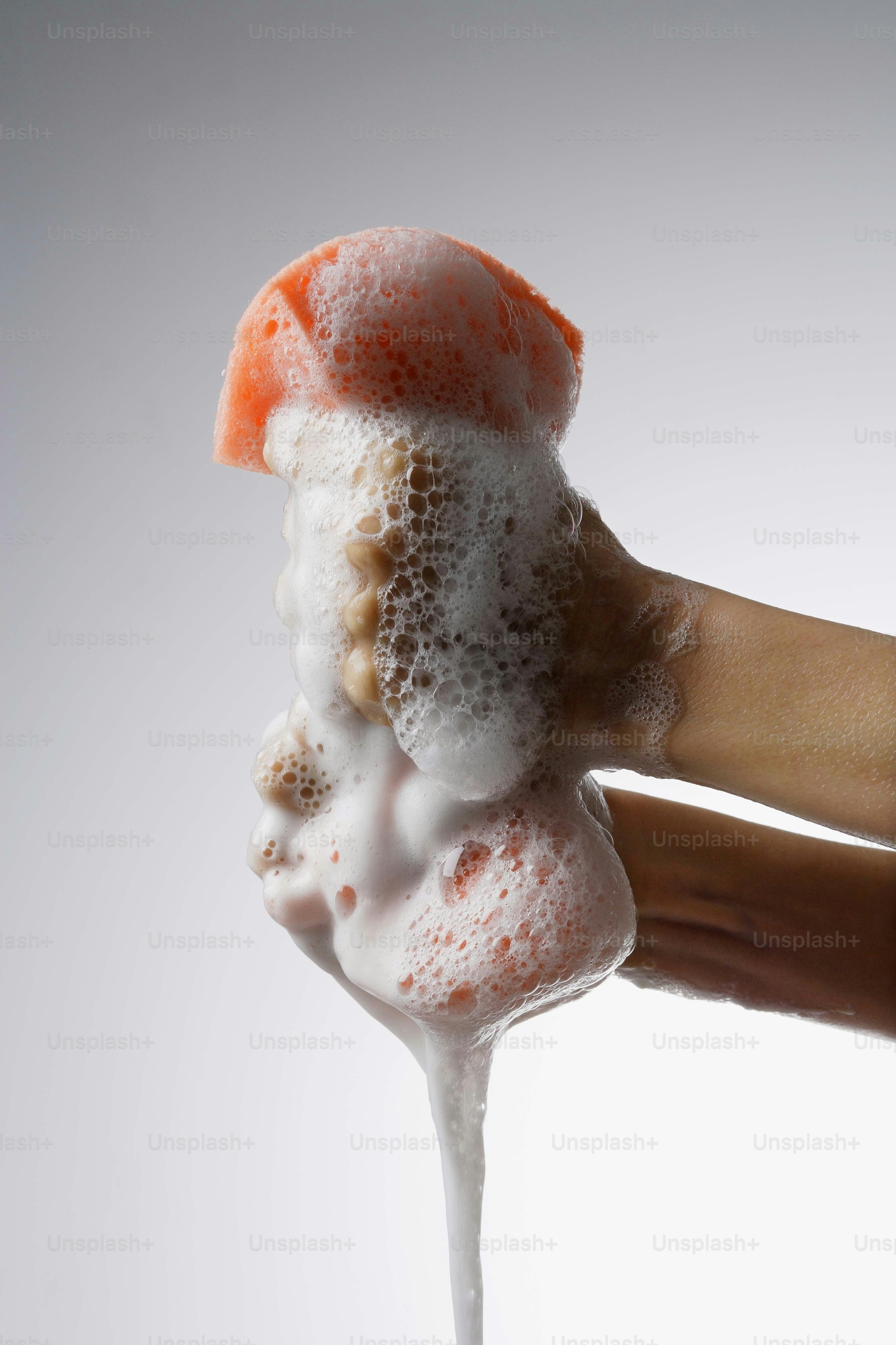 une main tenant une tranche de gâteau orange mousseuse