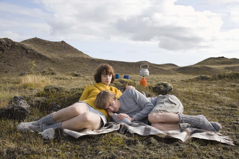 un couple de personnes allongé sur un champ couvert d’herbe