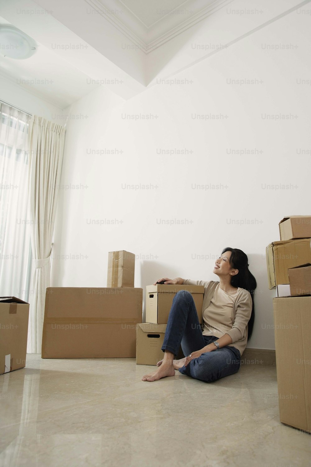 a woman sitting on the floor surrounded by boxes