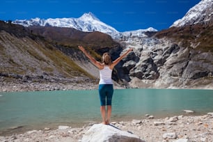 Une femme fait des exercices de yoga près d’un grand lac sur le circuit du Manaslu au Népal.