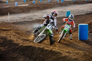two people riding dirt bikes on a dirt track