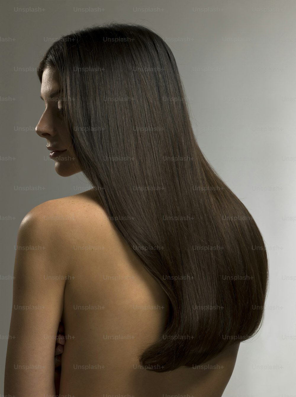 a woman with long brown hair standing in front of a white wall