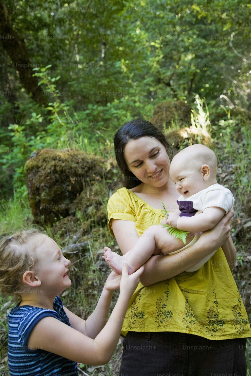 a woman holding a baby and two other children