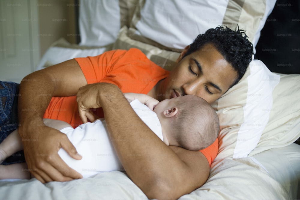 a man holding a baby while laying on a bed