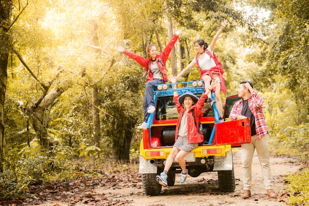 Viajeros jóvenes asiáticos felices con un automóvil de tracción 4WD fuera de la carretera en el bosque, una pareja joven que busca direcciones en el mapa y otros dos disfrutan en un automóvil de tracción 4WD. Joven mestizo asiático mujer y hombre.
