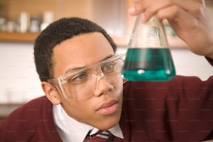 a man wearing glasses holding a beakle with a liquid in it