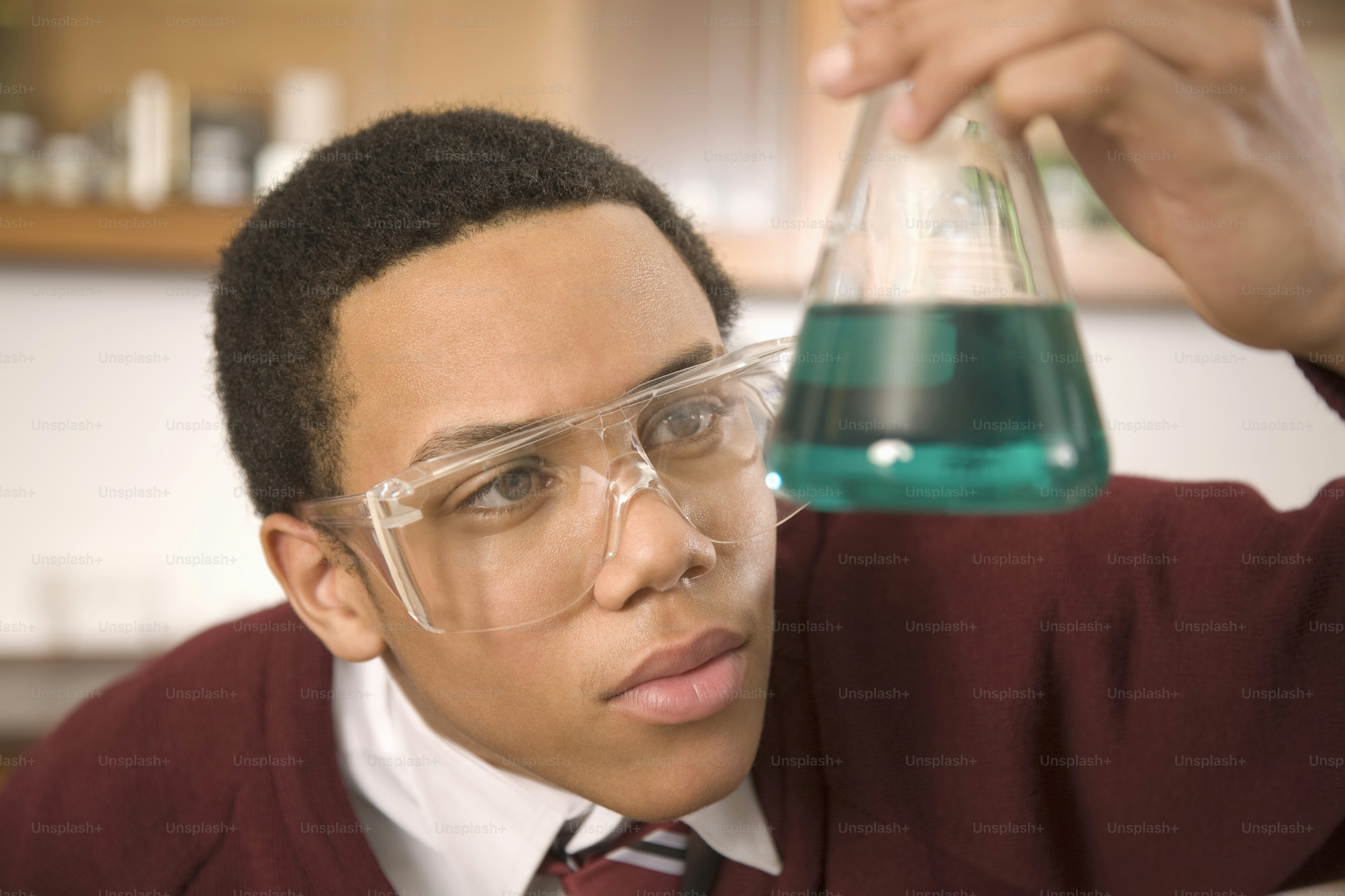 a man wearing glasses holding a beakle with a liquid in it