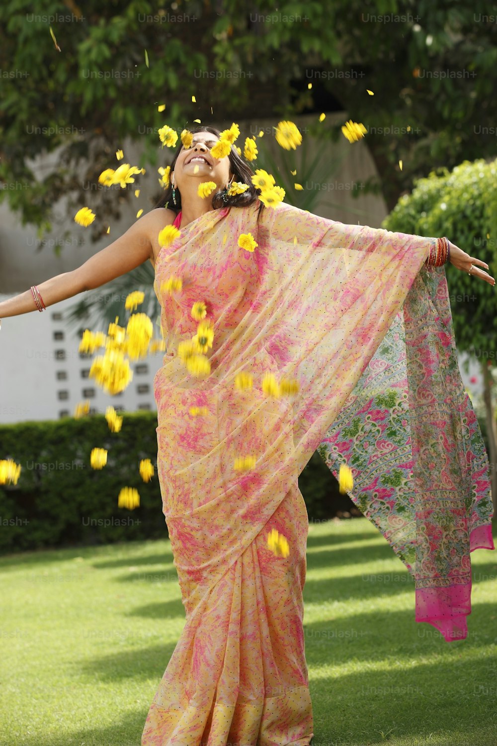 a woman in a sari throwing flowers in the air