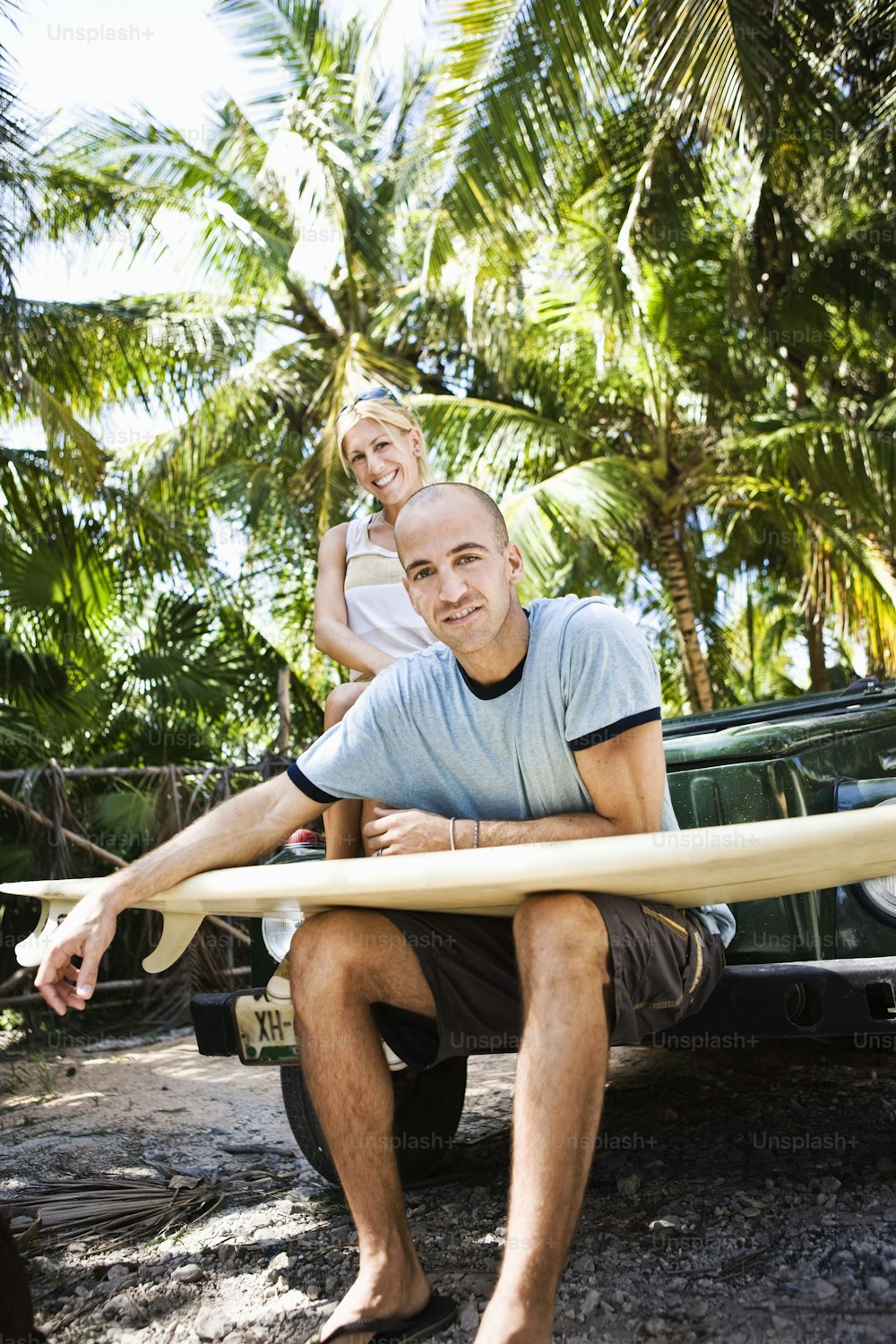 um homem segurando uma prancha de surf ao lado de uma mulher