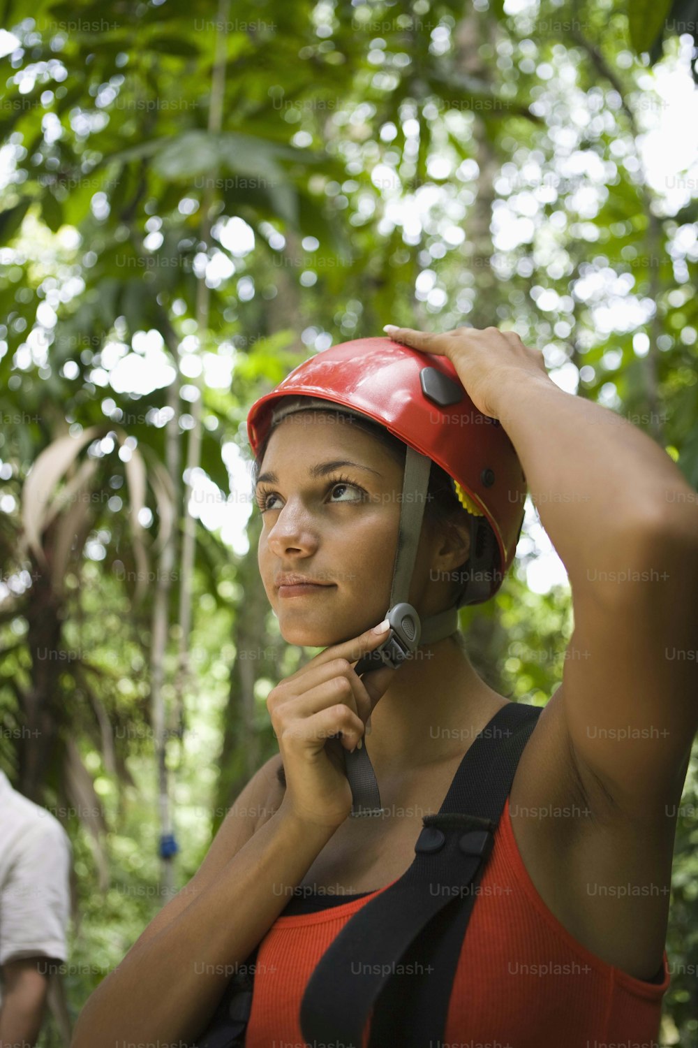 a woman wearing a helmet while standing in a forest