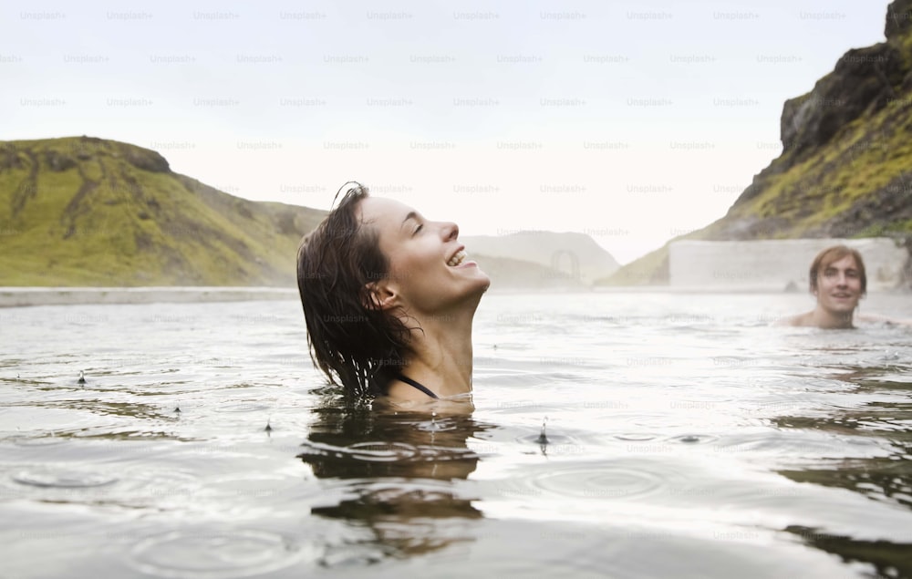Eine Frau in einem Gewässer mit Bergen im Hintergrund