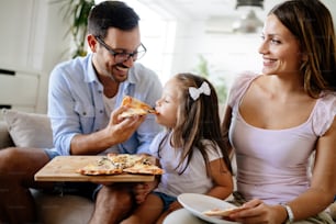 Familia feliz y sonriente compartiendo pizza juntos en casa