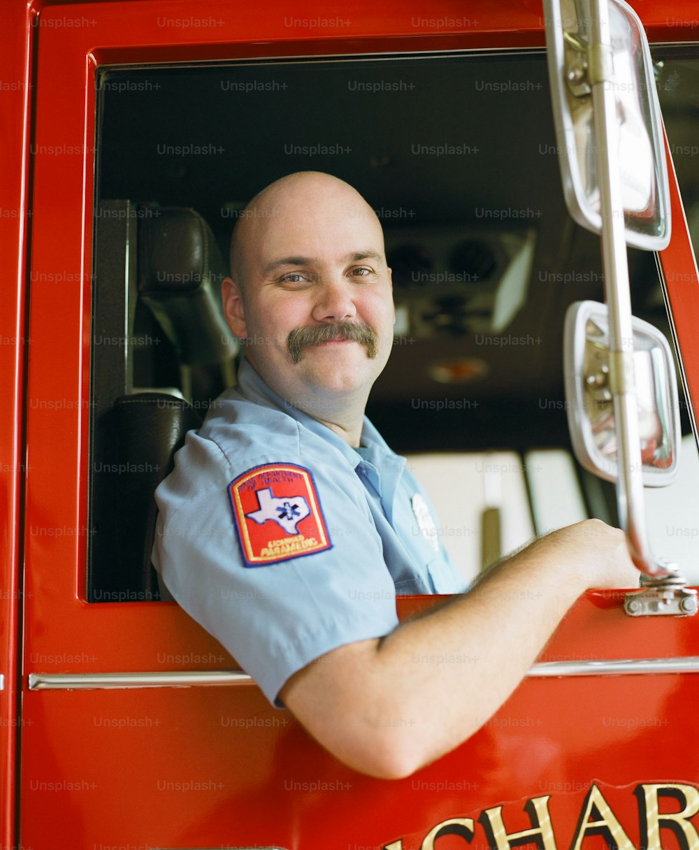 a man with a mustache is sitting in the driver's seat of a fire