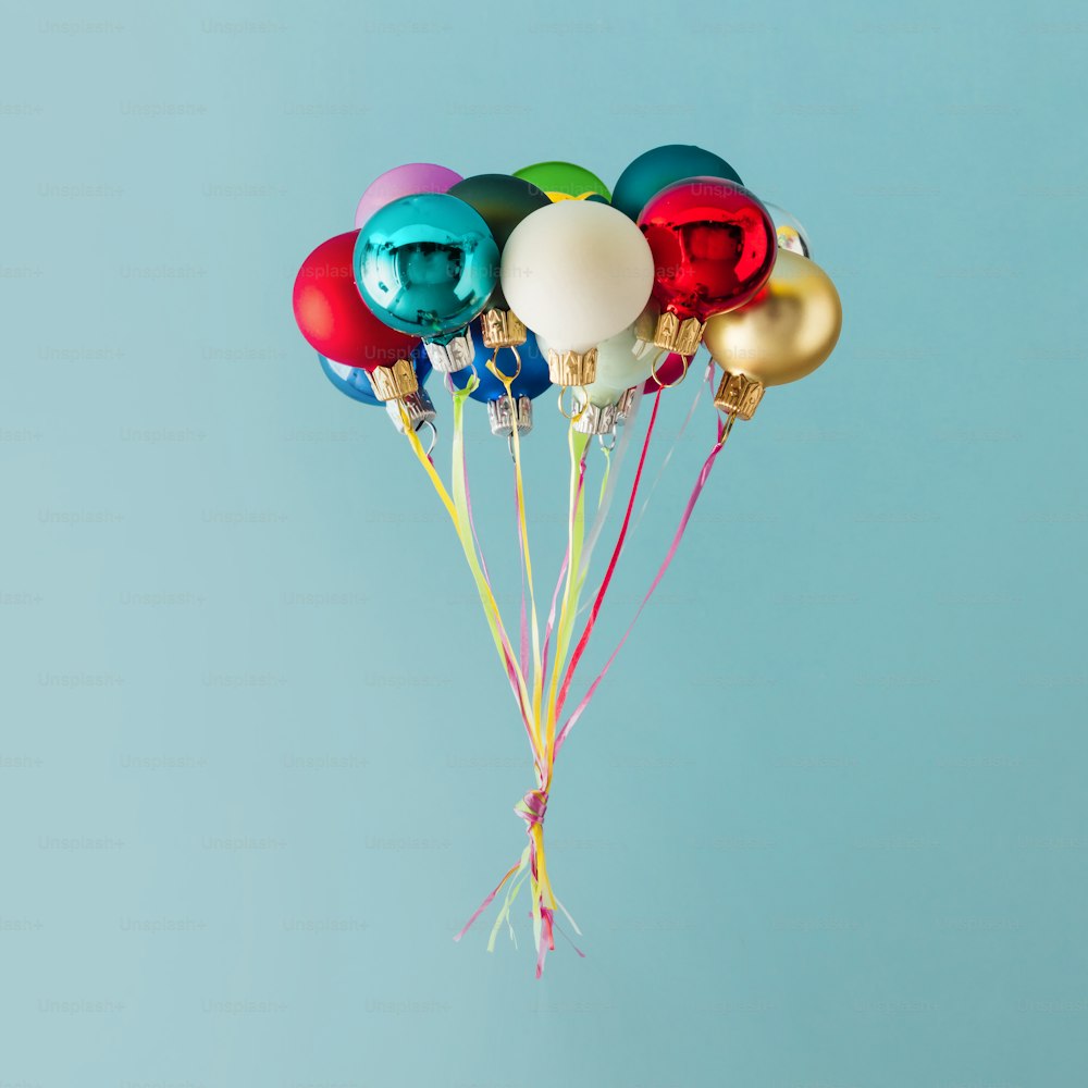Balloons made of colorful Christmas baubles decoration on blue background. Minimal Christmas concept.