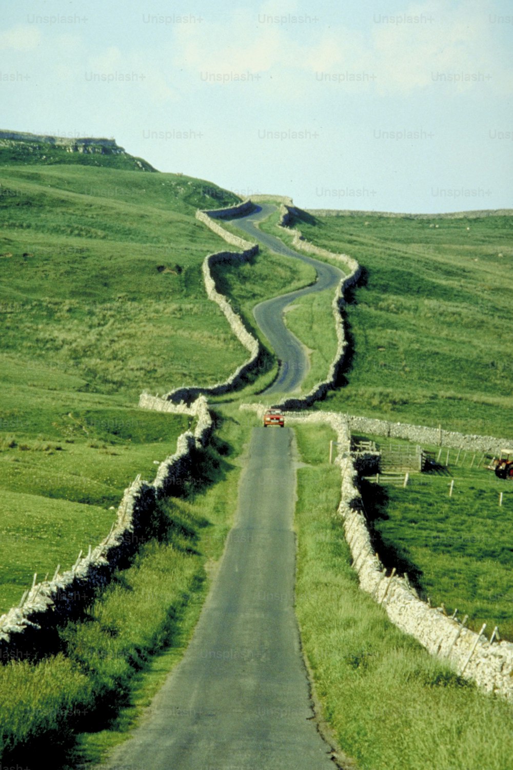 a winding road in the middle of a lush green field