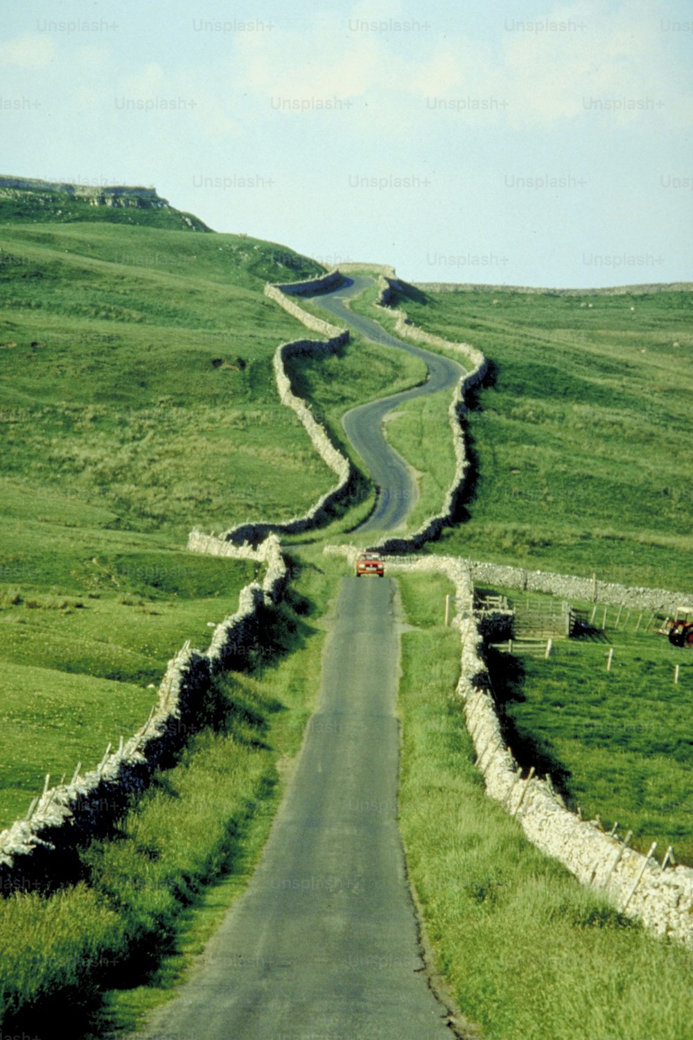 a winding road in the middle of a lush green field