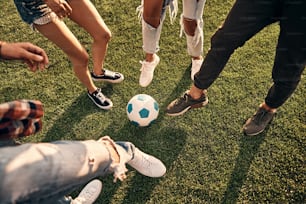Close-up of young people in casual wear playing soccer while spending time outdoors