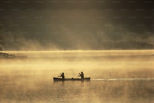 Deux personnes dans une barque à rames sur un lac brumeux