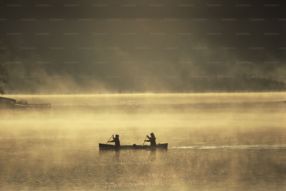 Duas pessoas em um barco a remo em um lago enevoado