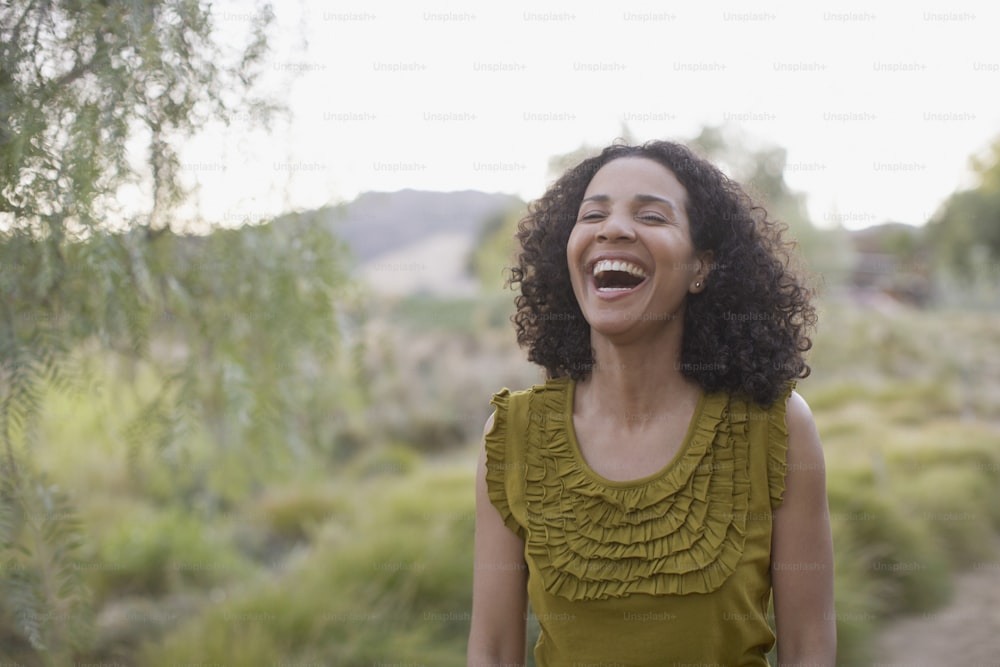 Una mujer riendo mientras está parada en un campo