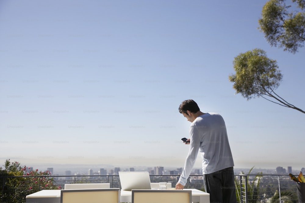 a man standing on top of a roof next to a laptop computer