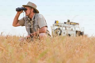 Un uomo seduto in un campo con una macchina fotografica