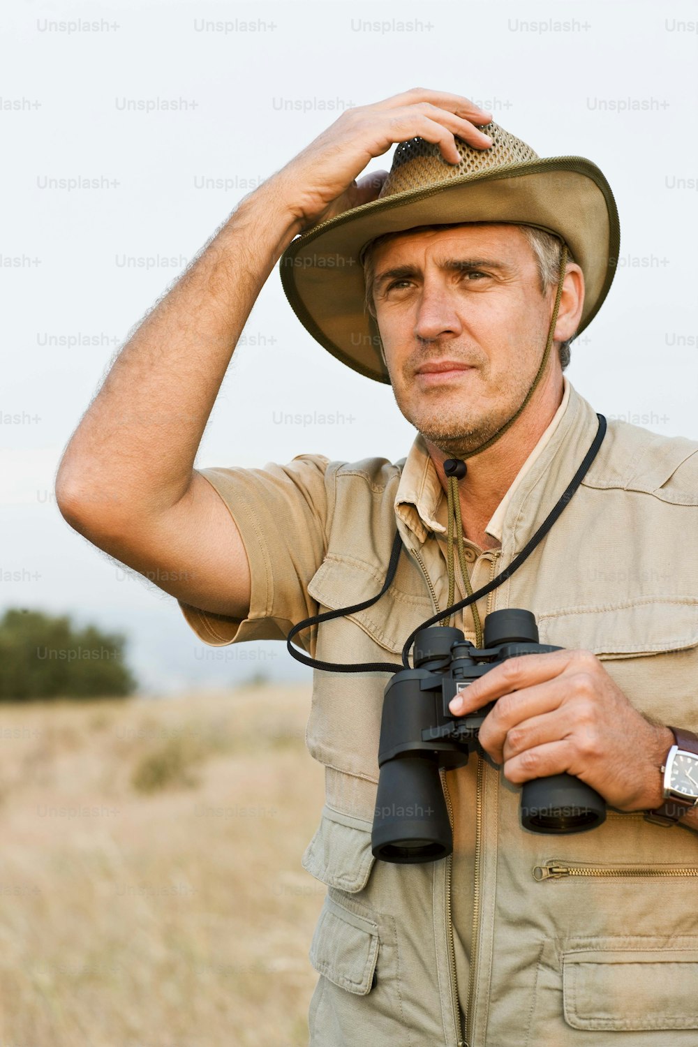um homem usando um chapéu e segurando um par de binóculos