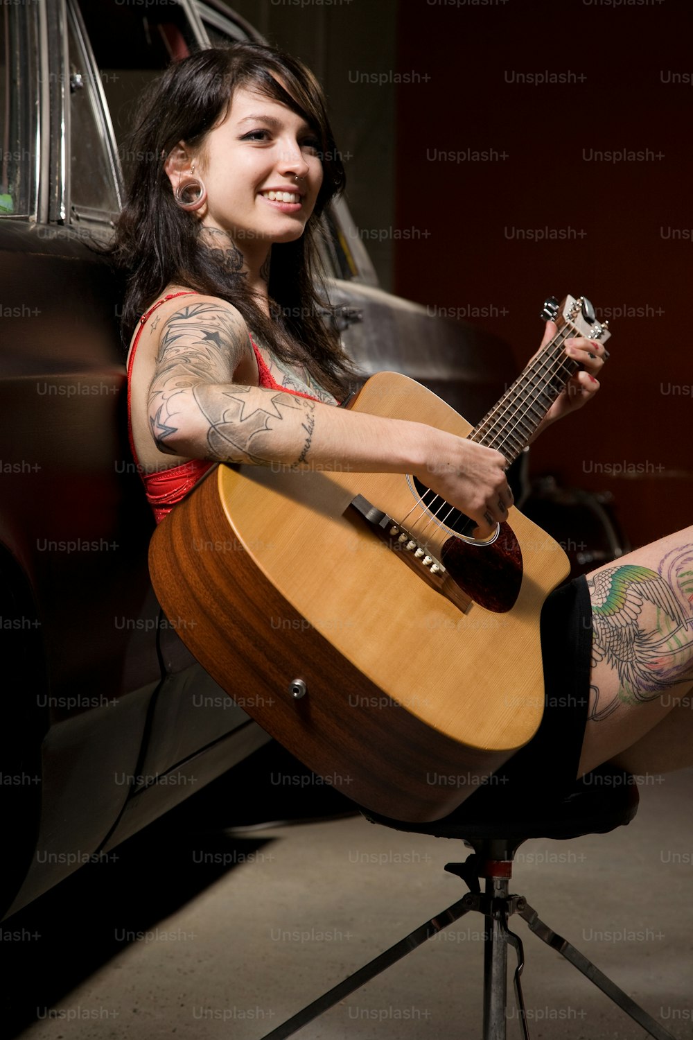 a woman sitting on a stool holding a guitar