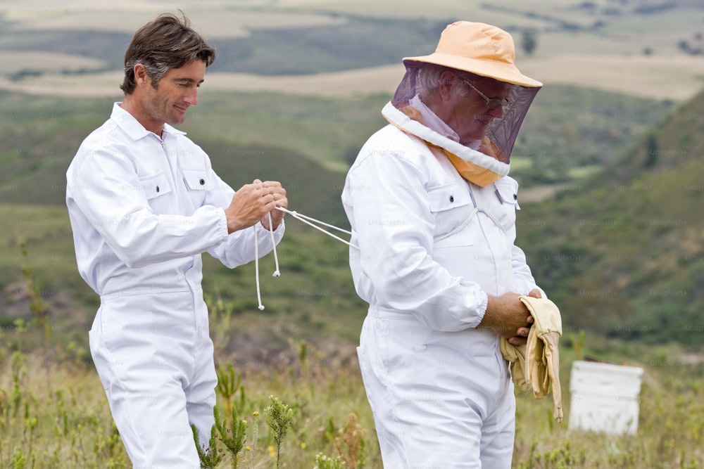 two men in bee suits standing in a field