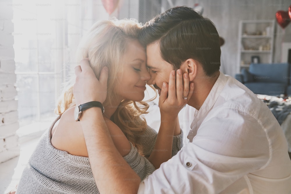 Beautiful young couple bonding and smiling while sitting in the bedroom