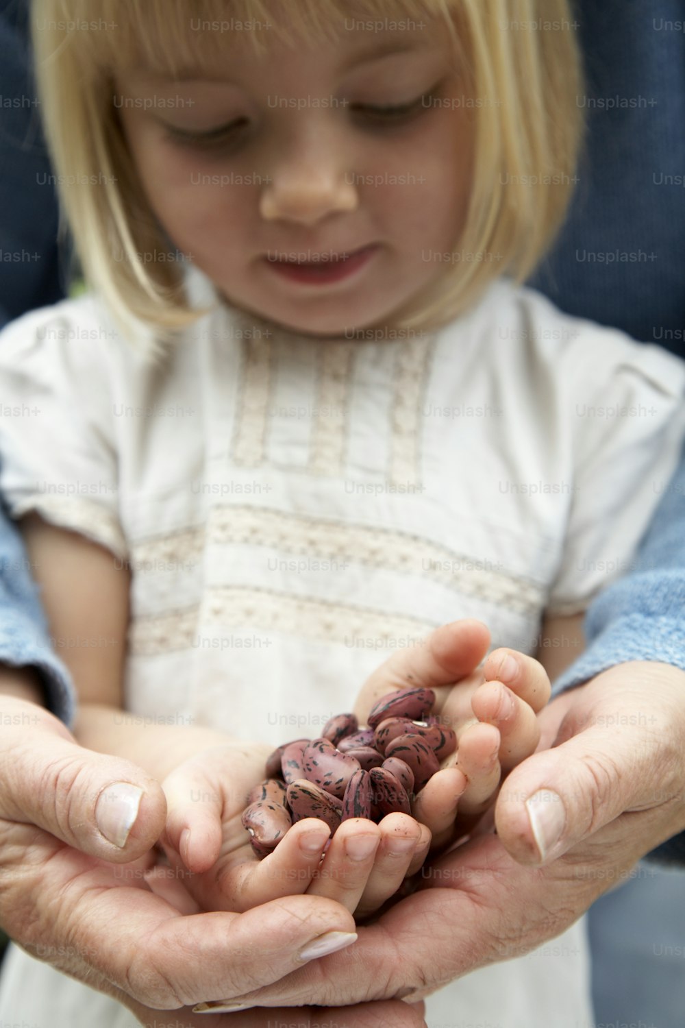 a little girl holding a handful of nuts in her hands