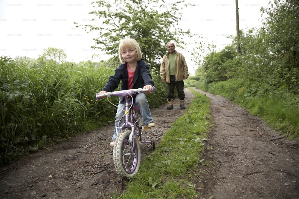 uma menina andando de bicicleta por uma estrada de terra