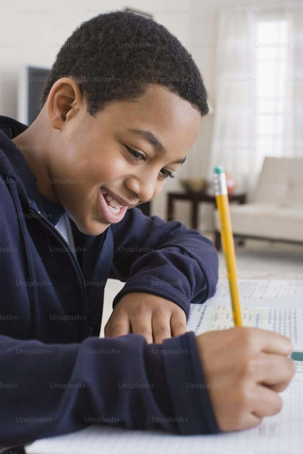 Um menino está sorrindo enquanto escreve em um pedaço de papel