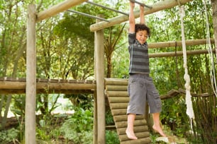 a young boy is playing on a wooden swing set