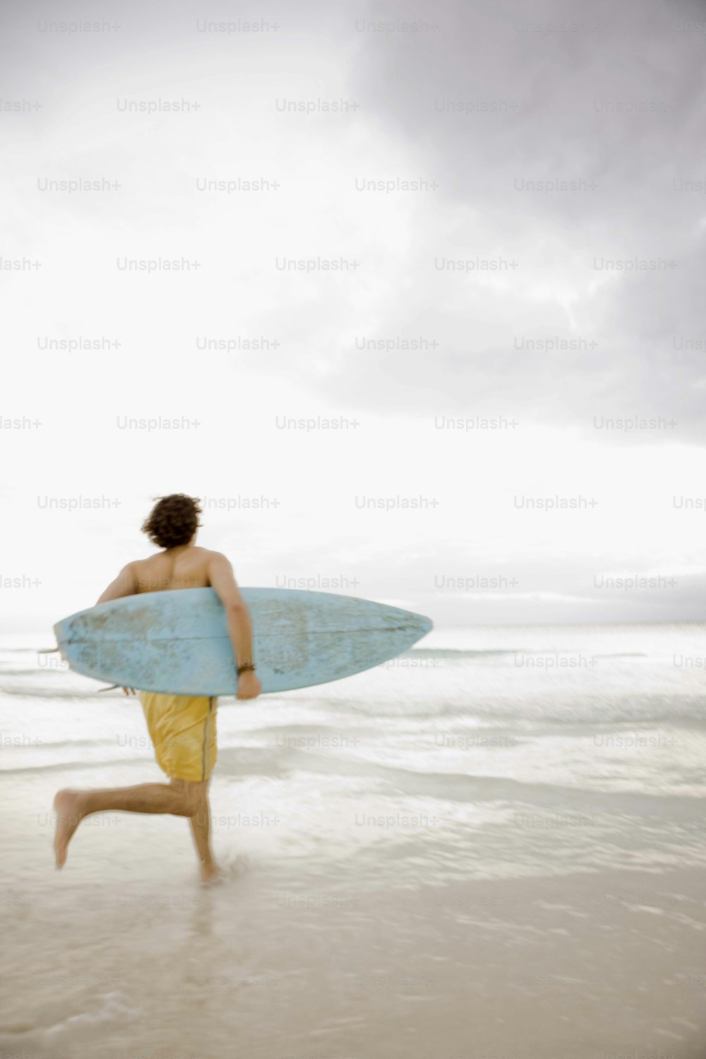 a man running on the beach with a surfboard