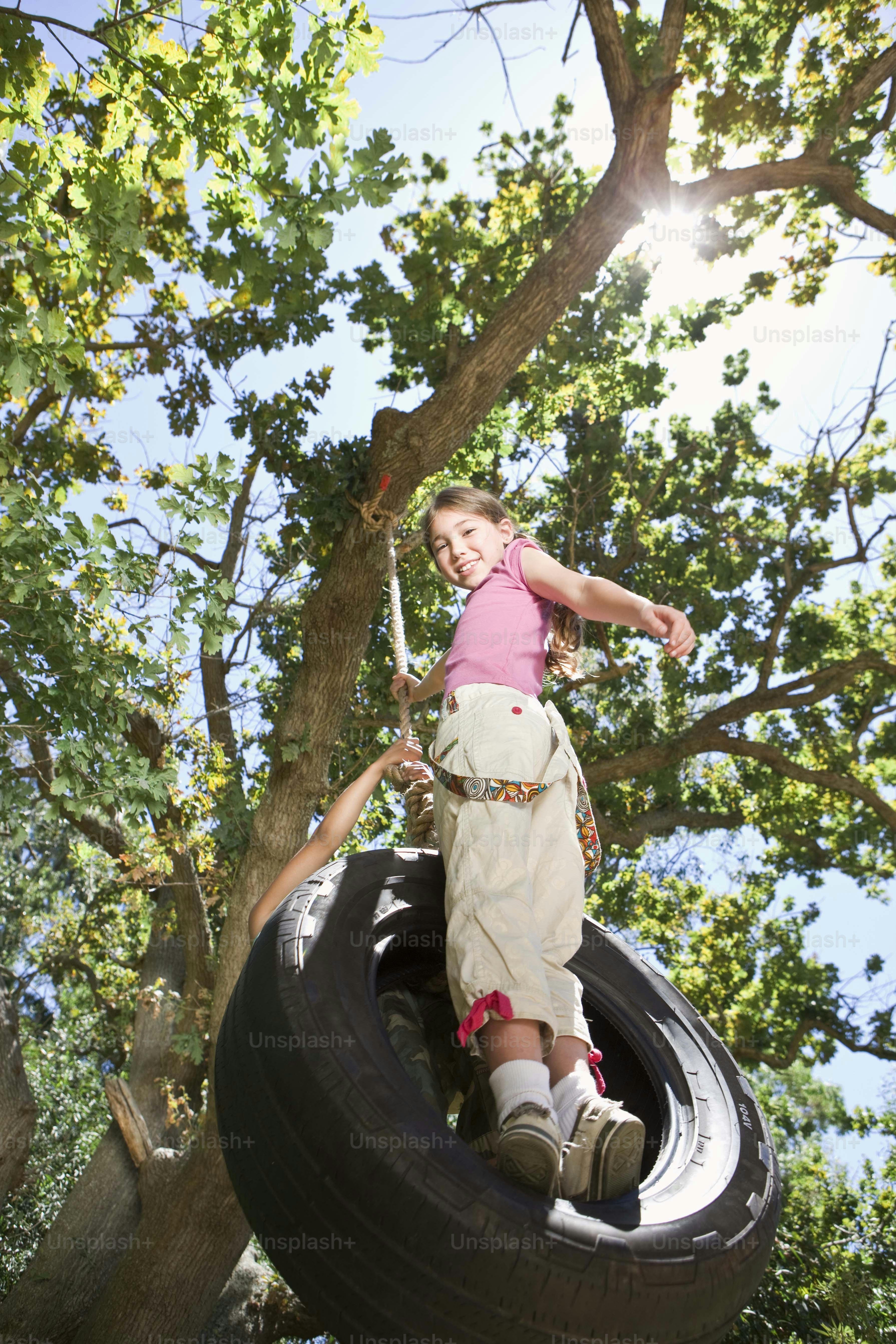a little girl in a pink shirt is on a tire