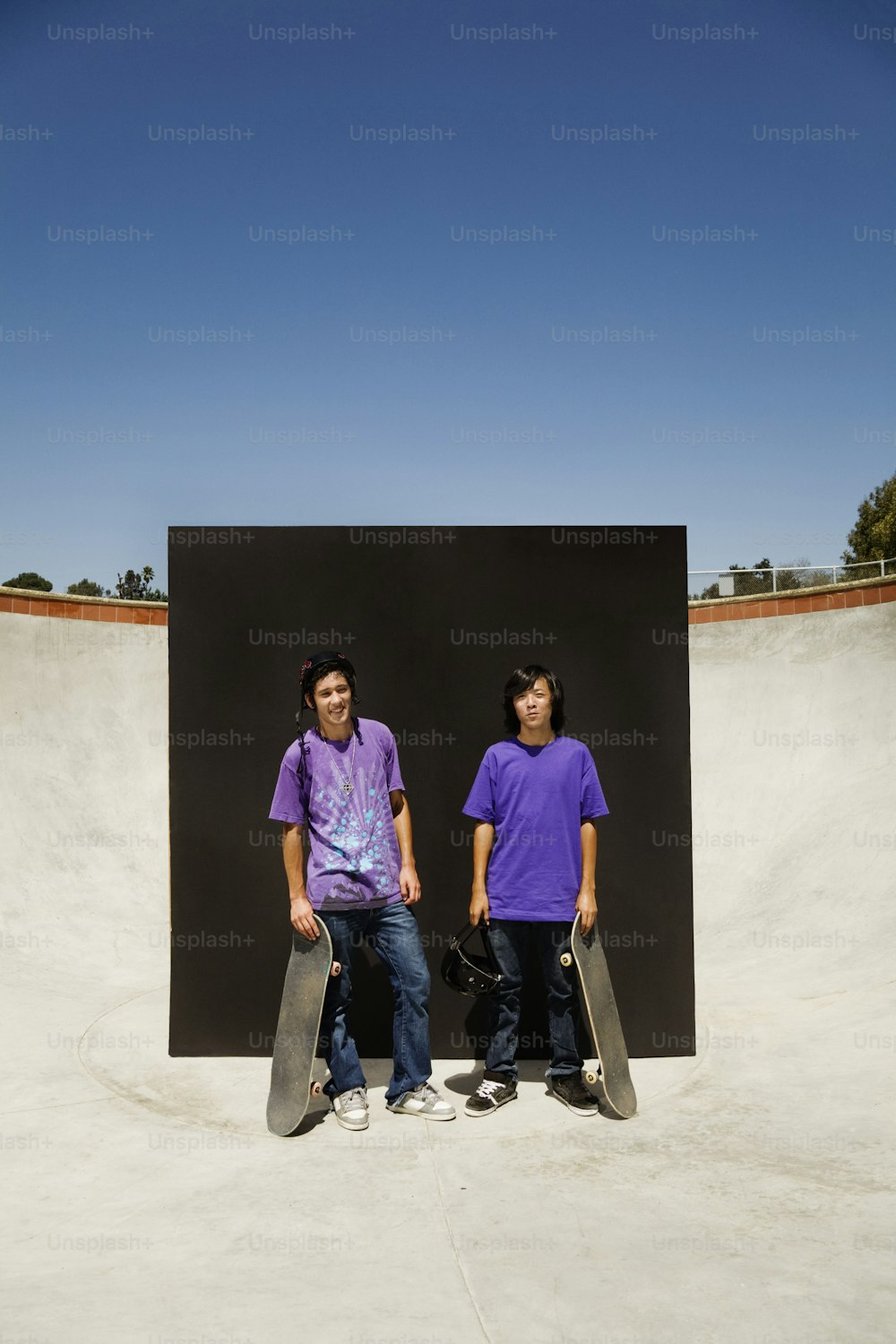 スケートボードを持って隣同士に立っている若い男性が数人