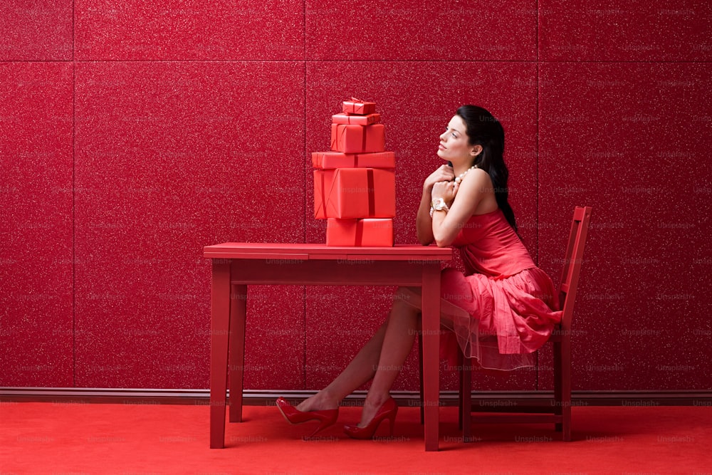 a woman in a red dress sitting at a red table