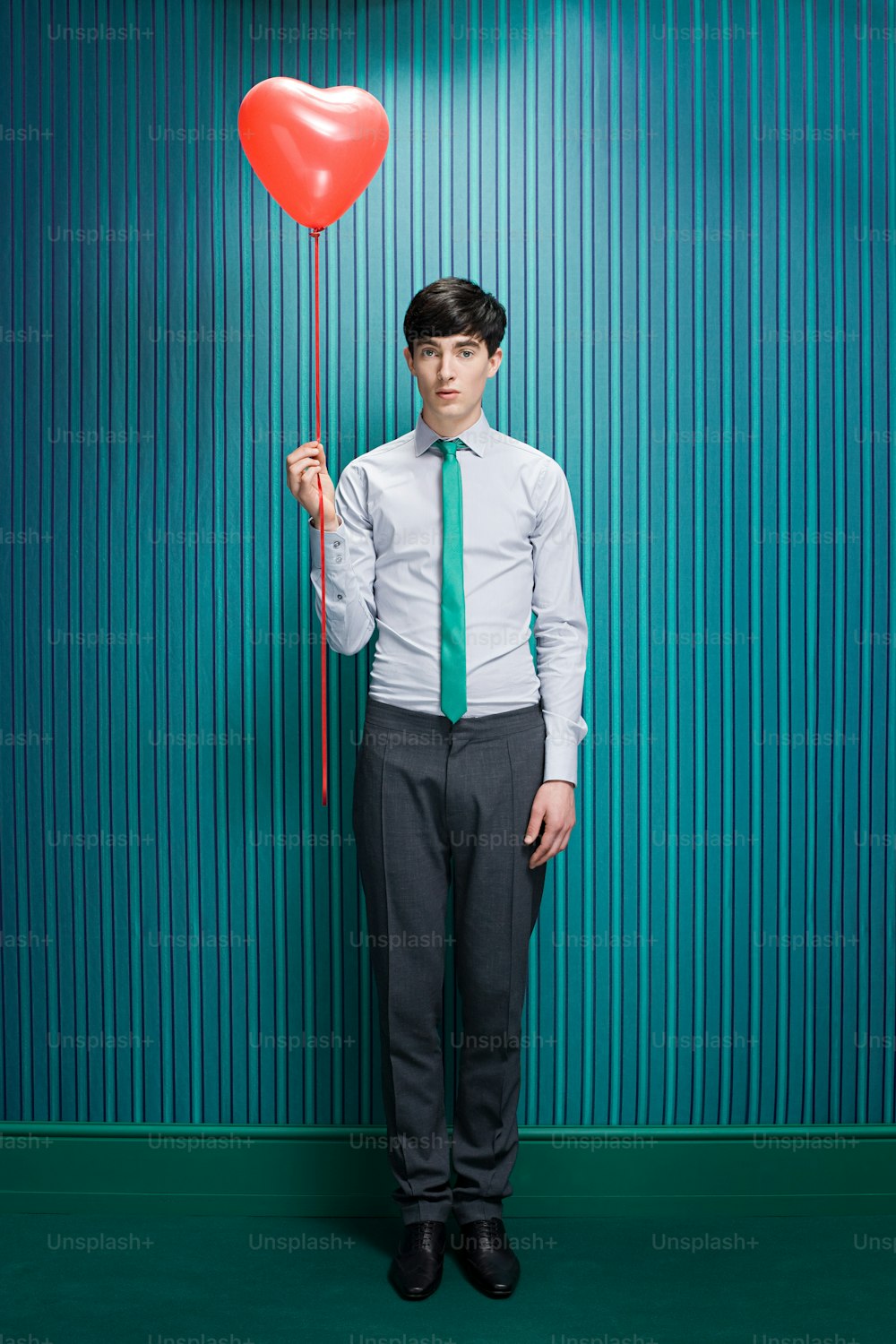 a man in a tie holding a heart balloon