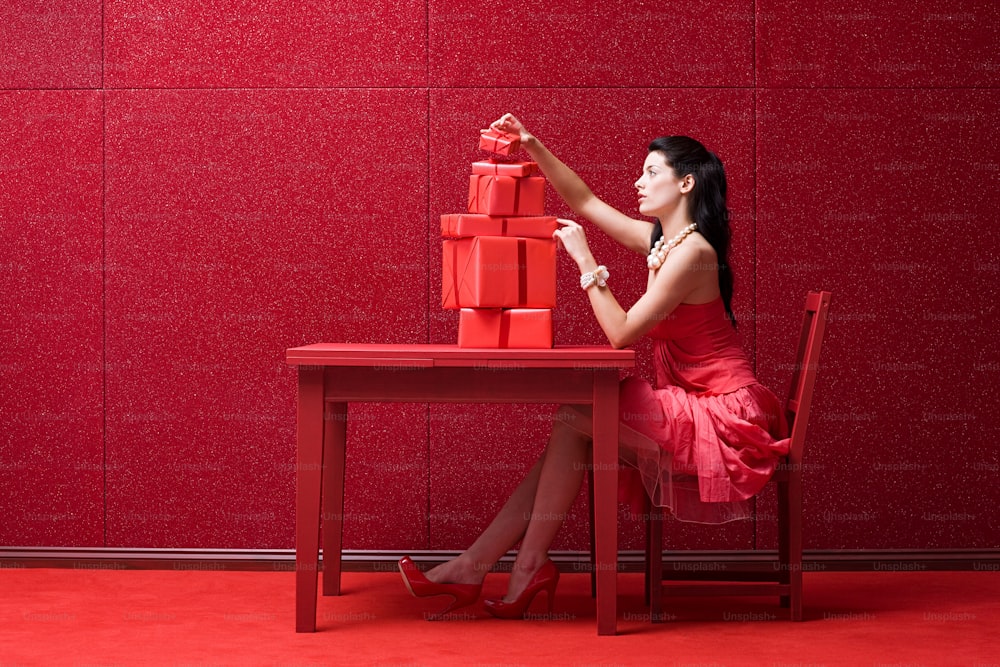 a woman in a red dress sitting at a red table