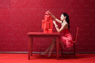 赤いテーブルに座っている赤いドレスを着た女性