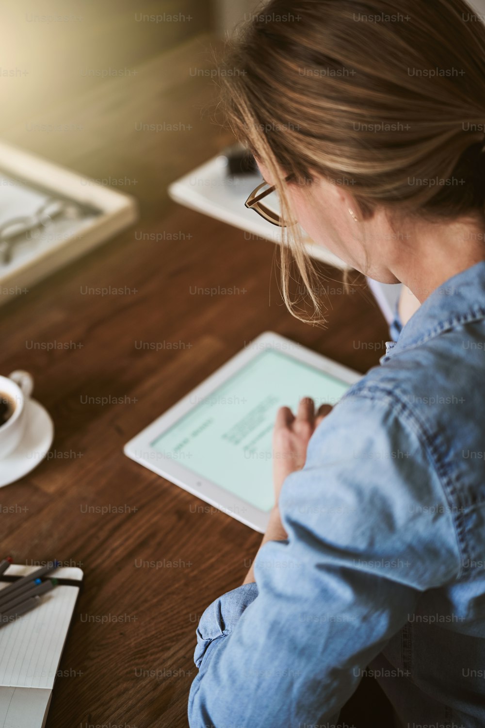 집에서 부엌 테이블에 혼자 앉아 디지털 태블릿으로 온라인으로 작업하는 젊은 여성