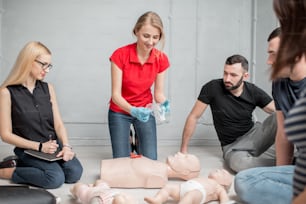 실내에서 응급 처치 그룹 훈련 중 인공 호흡을 위한 밸브��를 보여주는 젊은 여성 강사