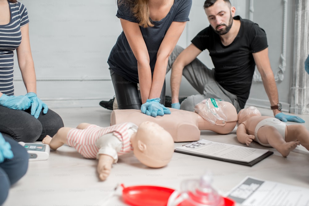 Groupe de personnes apprenant à faire des compressions cardiaques de premiers secours avec des mannequins pendant la formation à l’intérieur