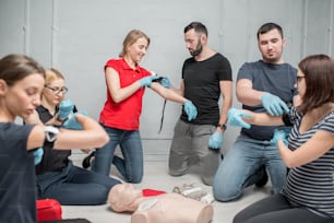 Eine Gruppe von Menschen, die lernen, den Tourniquet anzuwenden, um Blutungen während des Erste-Hilfe-Trainings in Innenräumen zu verhindern