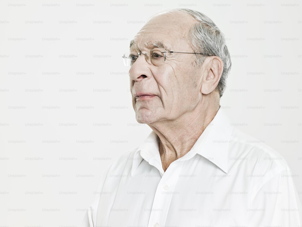 Un uomo anziano in una camicia bianca che guarda di lato