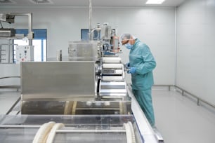 Pharmaceutical technician in sterile environment working with equipment at pharmaceutical manufacturing
