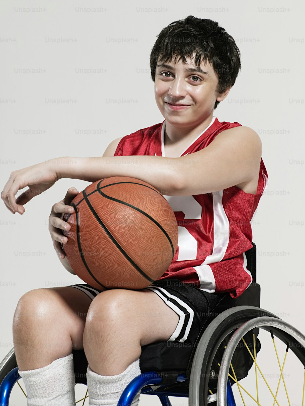 a boy in a wheelchair holding a basketball